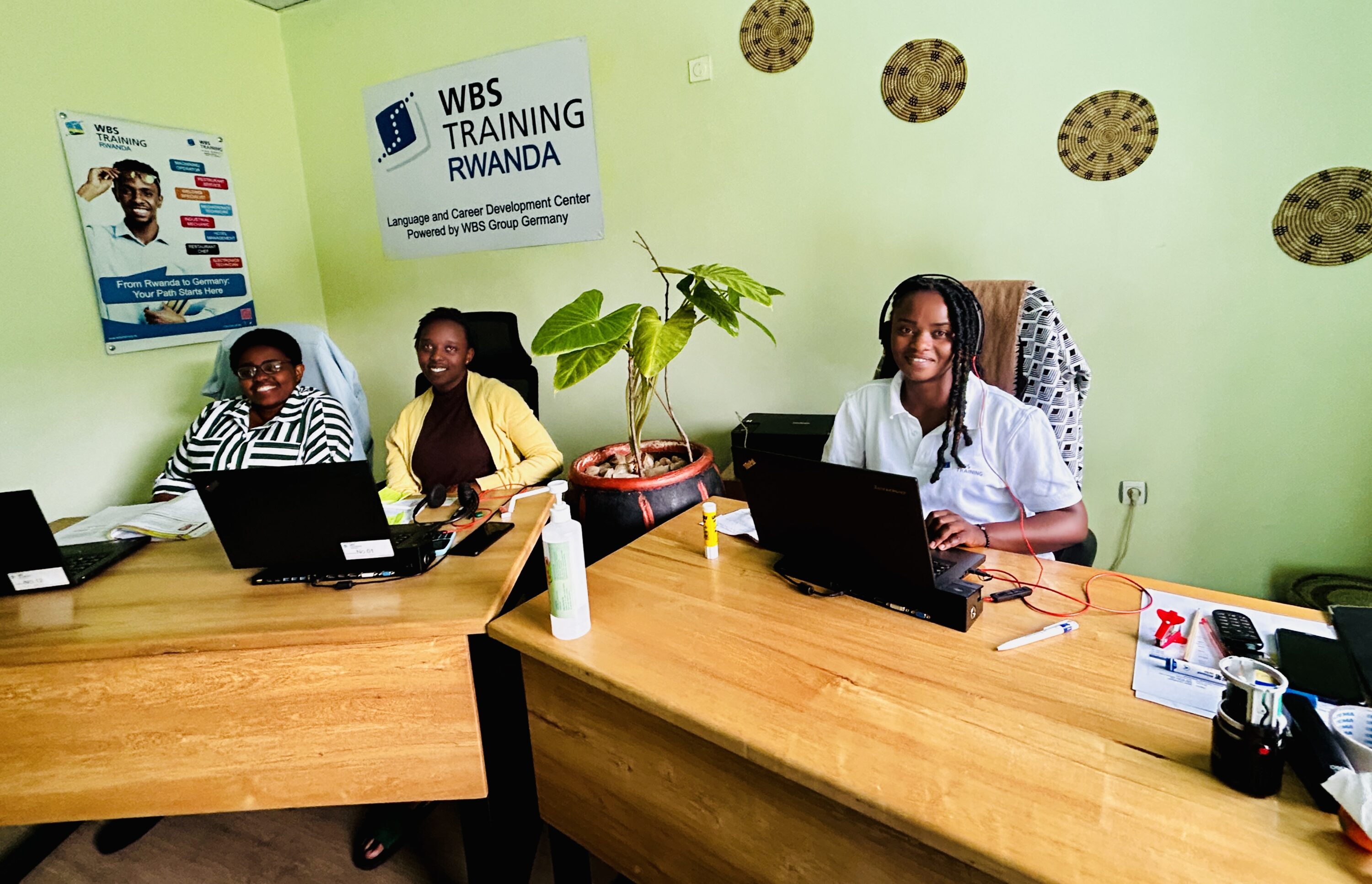Three female students at WBS Training Rwanda working on laptops in the training center.