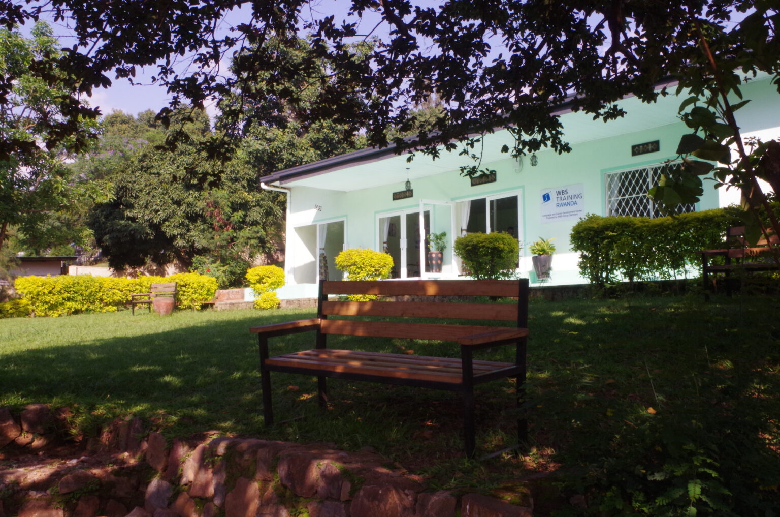 Exterior view of the WBS Training Rwanda center with garden and benches.